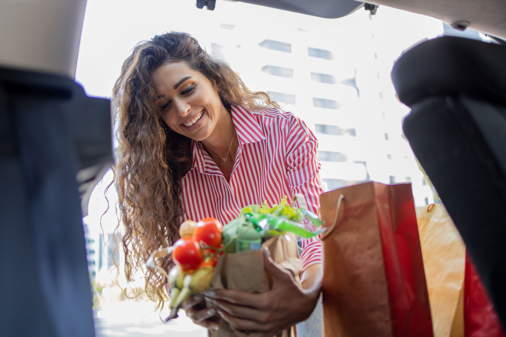 Young woman is taking groceries out of the trunk